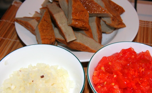 Chả cá mua về thái lát vừa ăn, có thể chần qua nước sôi rồi để ráo. Hành tây lột vỏ, thái nhỏ. Cà chua bằm nhỏ.